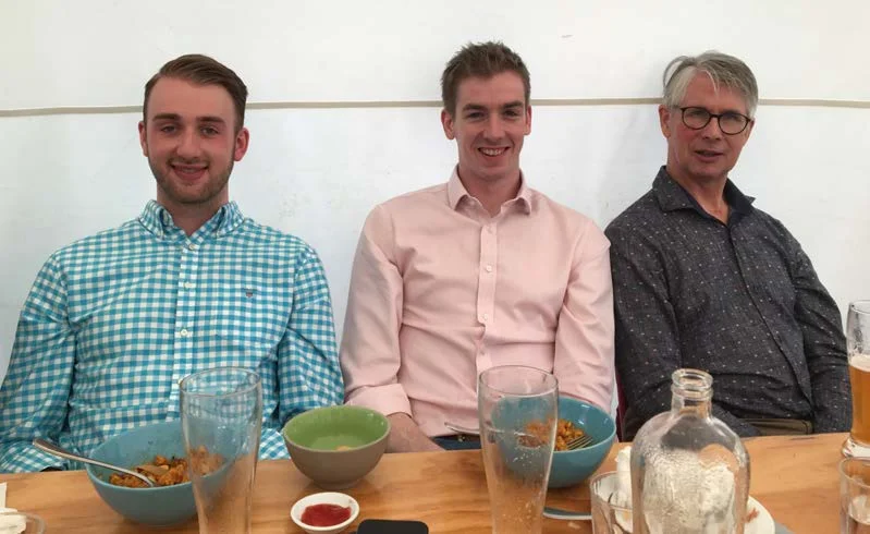 Three men sitting at a table with bowls of food